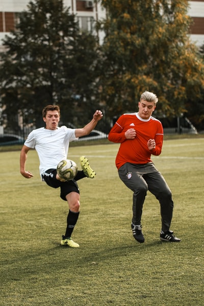 Two men wearing red shirts to play football in the daytime
